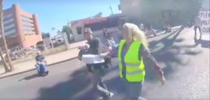 A person who identified herself as a parade organizer (right in neon yellow) is videotaped hitting a Veterans Day Parade participant.